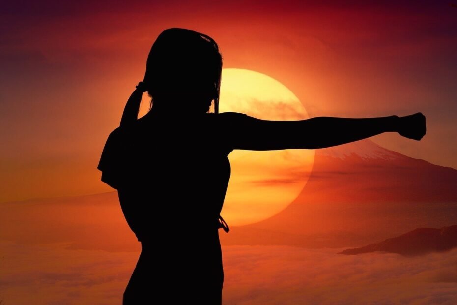 Woman silhouette punching with sun in background